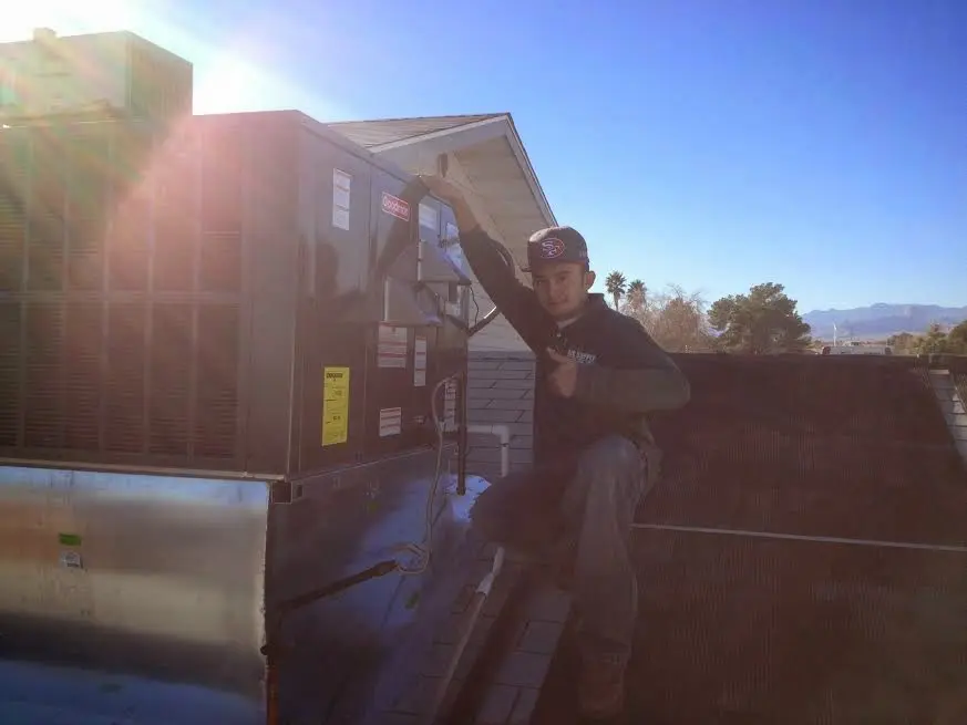 HVAC technician performing AC Tune-Up on a rooftop unit in Laurel